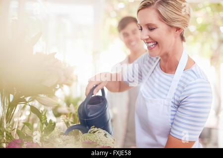 Sorridente fioraio fiori di irrigazione nel negozio di fiori Foto Stock