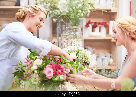 Disponendo di fiorista bouquet per il cliente nel negozio di fiori Foto Stock