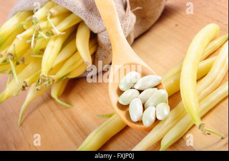 Semi di fagioli sul cucchiaio di legno e heap di fagioli nel sacco di iuta giacente sul tavolo di legno, sana alimentazione e nutrizione Foto Stock