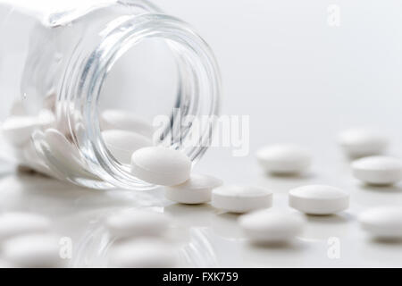 Grappolo di pillole di bianco sentito fuori dal flacone r sul tavolo Foto Stock
