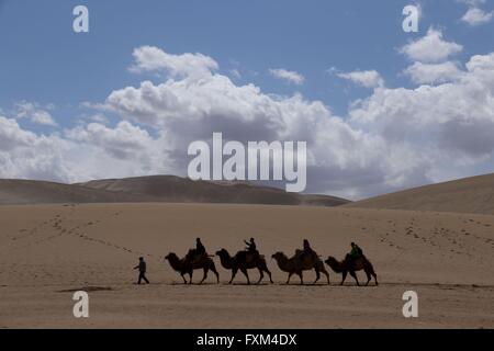 Jiuquan, la Cina della provincia di Gansu. Xvi Apr, 2016. Persone corsa cammelli al Crescent Lake scenario spot in montagna Mingsha di Dunhuang City, a nord-ovest della Cina di Provincia di Gansu, Aprile 16, 2016. Dunhuang City ha dimostrato la sua naturale bellezza dopo una pioggia di Sabato. Credito: Zhang Xiaoliang/Xinhua/Alamy Live News Foto Stock