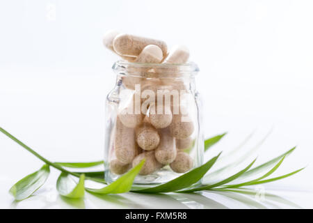 Farmaci a base di erbe capsule in una bottiglia di vetro isolato su sfondo bianco ritaglio. Foto Stock