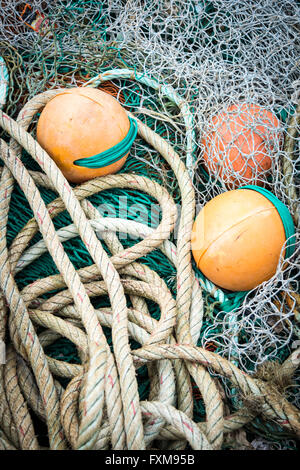 Le reti da pesca, boe, funi e attrezzature su una banchina di un porto nel Regno Unito Foto Stock