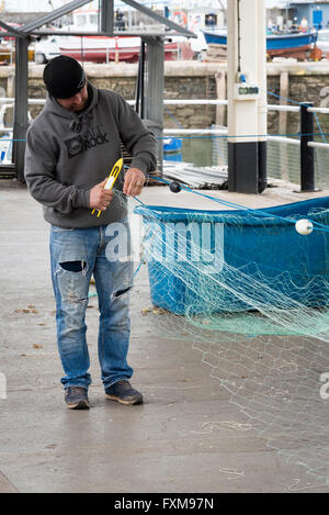 I pescatori riassettavano le reti da pesca sulla banchina a Brixham Devon UK Foto Stock