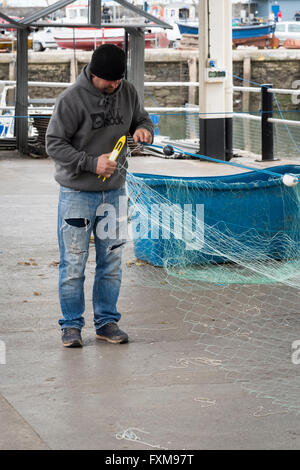 I pescatori riassettavano le reti da pesca sulla banchina a Brixham Devon UK Foto Stock