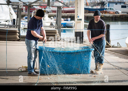 I pescatori riassettavano le reti da pesca sulla banchina a Brixham Devon UK Foto Stock