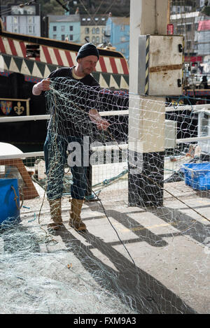 I pescatori riassettavano le reti da pesca sulla banchina a Brixham Devon UK Foto Stock