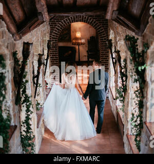 Sposa felice coppia sposata andando giù per le scale e tenendo le mani Foto Stock