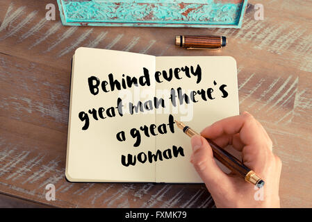 Effetto retrò e tonico immagine di una donna la scrittura a mano su un notebook. Preventivo scritto a mano dietro ogni grande uomo c'è una grande donna come concetto ispiratore immagine Foto Stock