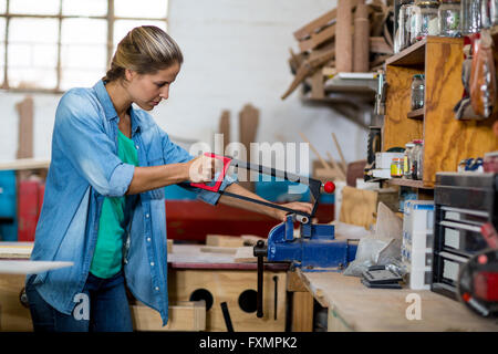 Falegname femmina utilizzando affrontando sega per tagliare il pezzo di legno Foto Stock