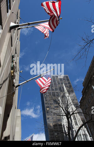 Bandiere che sventolano sulla Quinta Avenue di New York nella parte anteriore di un grattacielo e St Patricks Cathedral Foto Stock