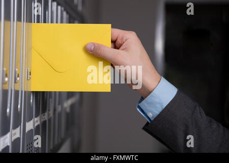 Stretta di mano di mettere la lettera gialla nella mailbox Foto Stock