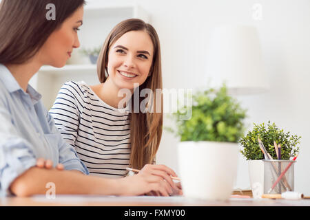 Allegro ragazza seduta al tavolo Foto Stock