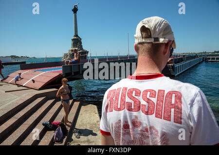 Un uomo con la scritta Russia sulla t-shirt in piedi sul lungomare nel centro della città di Sebastopoli, Repubblica Crimea Foto Stock