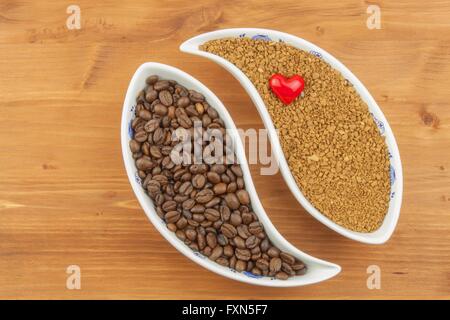 Naturale di chicchi di caffè rispetto all'istante. Solubili e i chicchi di caffè su sfondo di legno. La preparazione di caffè fresco. Foto Stock