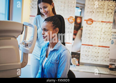 Grave donna nera con coda di cavallo e indossa blu jean shirt occhio prende in esame il negozio OTTICA Foto Stock