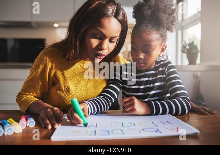 Nero la madre e il bambino a fare i compiti di scuola, imparare l'alfabeto Foto Stock