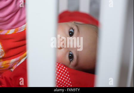 Dieci mese bambina dietro il bar bianco cot Foto Stock