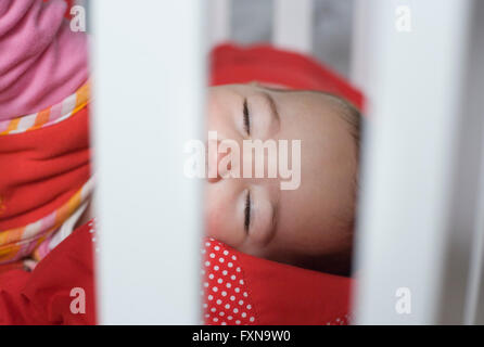 Dieci mesi ragazza bambino dorme dietro il bar bianco cot Foto Stock