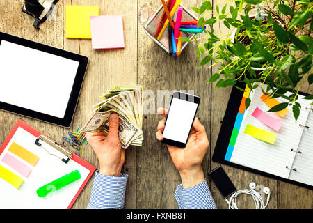 Le mani di uomo con dollari USA e lo smartphone Foto Stock
