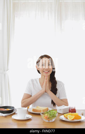 Attraente giovane donna giapponese avente la colazione a casa Foto Stock