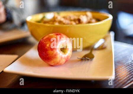 Apple su una piastra bianca con una forchetta e insalatiera con profondità di campo Foto Stock