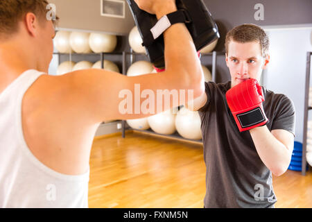 Due uomini focalizzato boxing training presso la palestra fitness Foto Stock