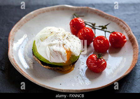 La colazione, i funghi con avocado e uova in camicia e arrostire i pomodori ciliegia sulla vite Foto Stock