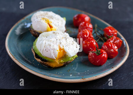 La colazione, i funghi con avocado e uova in camicia e arrostire i pomodori ciliegia sulla vite Foto Stock