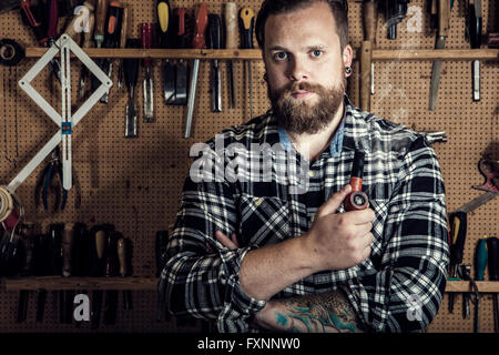 Ritratto ambientale di un uomo di fumare tubo in officina in legno Foto Stock