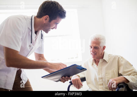 L'infermiera che mostra uomo senior di un documento Foto Stock