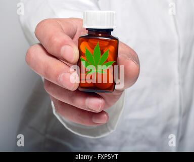 Persona in possesso di una pillola flacone contenente medicinali marijuana. Foto Stock