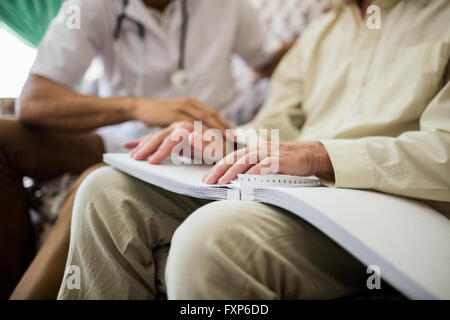 Senior cieco uomo usando il braille per leggere Foto Stock