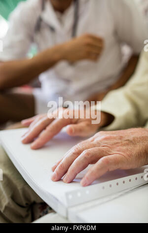 Senior cieco uomo usando il braille per leggere Foto Stock