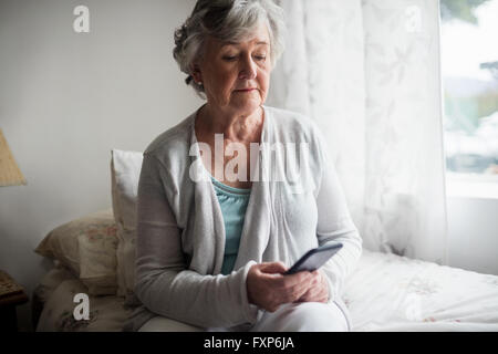 Senior donna inviando un messaggio con il suo smartphone Foto Stock