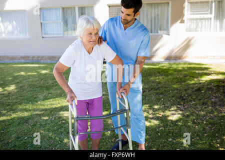 L'infermiera aiutando senior donna a camminare Foto Stock