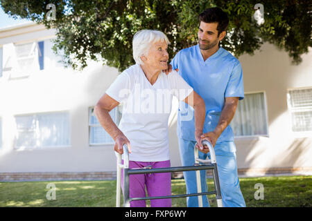 L'infermiera aiutando senior donna a camminare Foto Stock