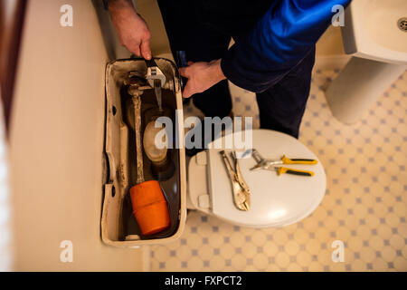 Plumber riparazione di una cassetta di risciacquo Foto Stock