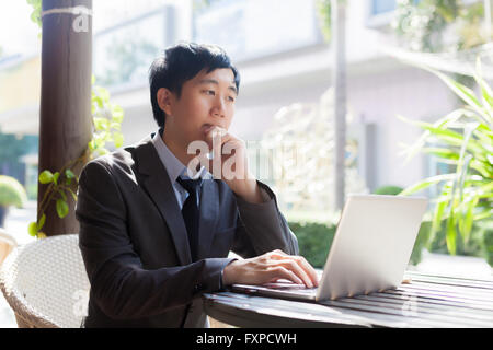 Giovani asiatici imprenditore casual pensare mentre si lavora in scena all'aperto Foto Stock