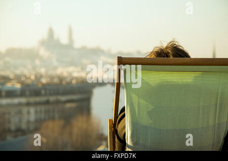 Persona seduta in sedia a sdraio, guardando alla vista della città Foto Stock