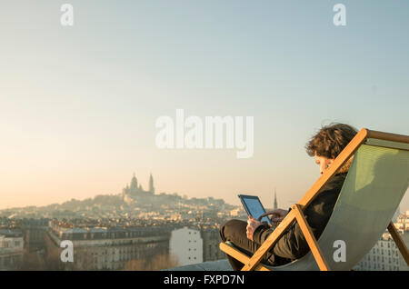 Uomo in relax sulla terrazza sul tetto con tavoletta digitale Foto Stock