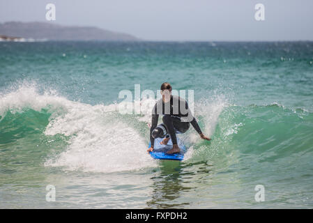 Un uomo che cavalca il suo surfboard verso la riva. A sette miglia dal centro di Sydney, nota Manly Beach Foto Stock