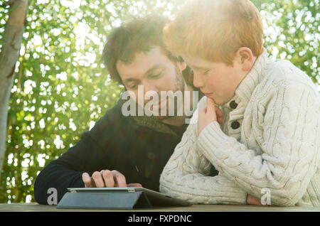 Padre e figlio guardando a tavoletta digitale insieme Foto Stock