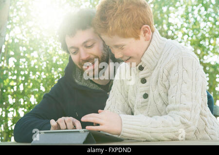Padre e figlio guardando a tavoletta digitale insieme Foto Stock