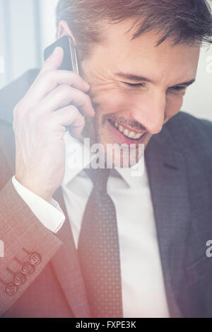 Imprenditore parlando al cellulare, sorridente Foto Stock