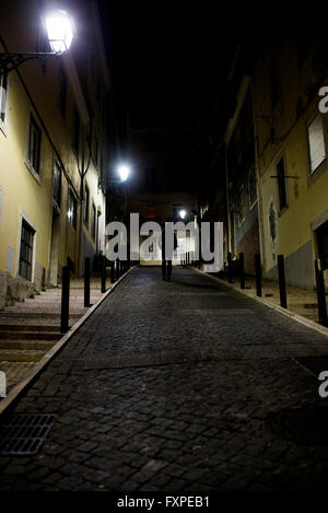 Uomo che cammina sulla strada di ciottoli di notte Foto Stock