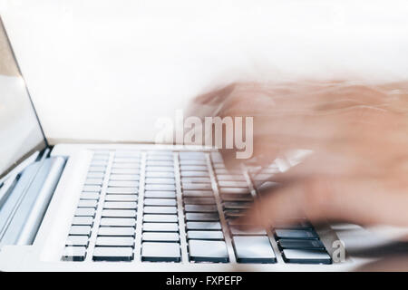 Close-up di mani umane digitando su laptop in movimento sfocate con copia spazio sopra (messa a fuoco selettiva) Foto Stock