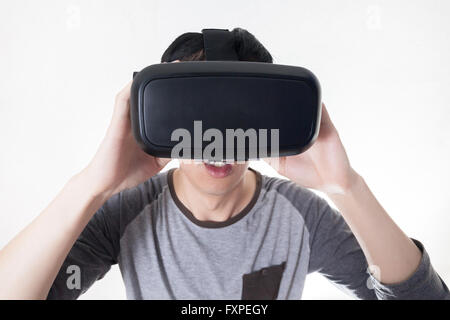 Uomo asiatico indossando VR goggle e immergendosi in VR multimedia in bianco isolato. Foto Stock