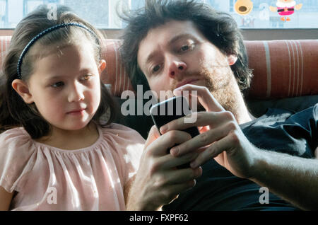 Padre e figlia giovane guardando insieme allo smartphone Foto Stock