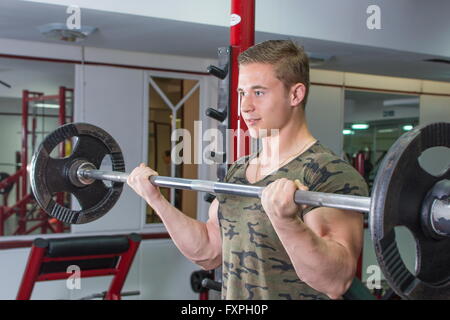 L'uomo eseguendo barbell curl in palestra. Allenamento bicipiti Foto Stock